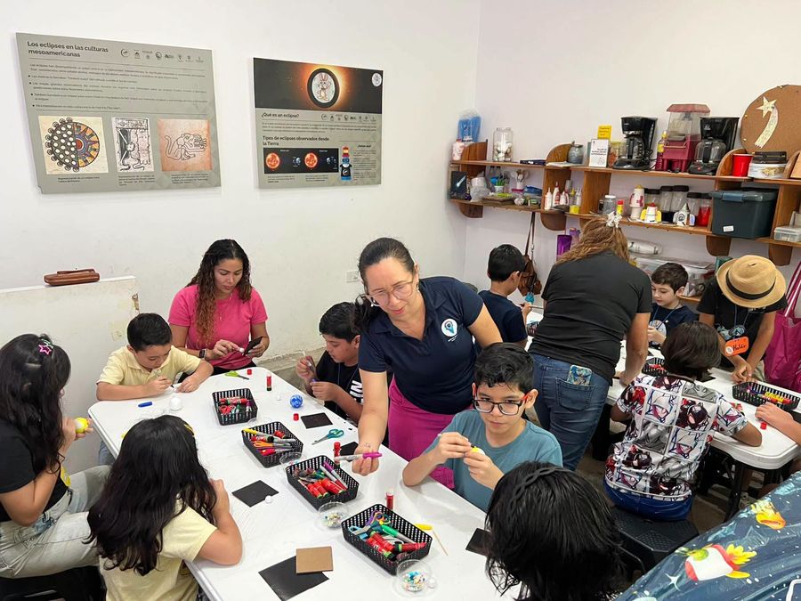 Una instructora de SAMAZ ayuda a un niño a pintar su planeta de unicel.
